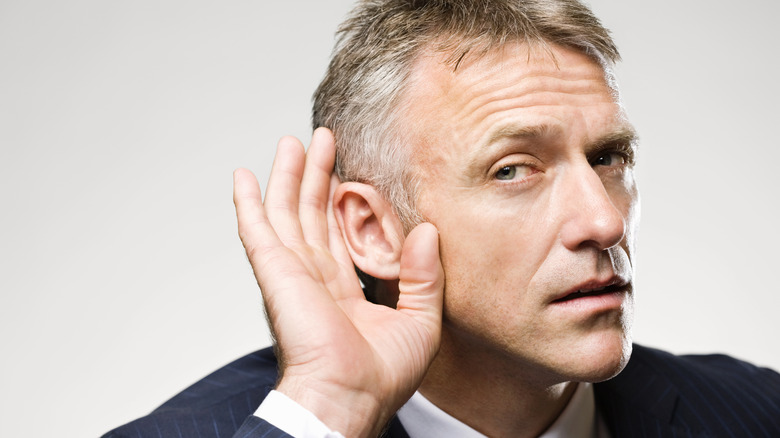 A man is holding his hand to his ear while listening