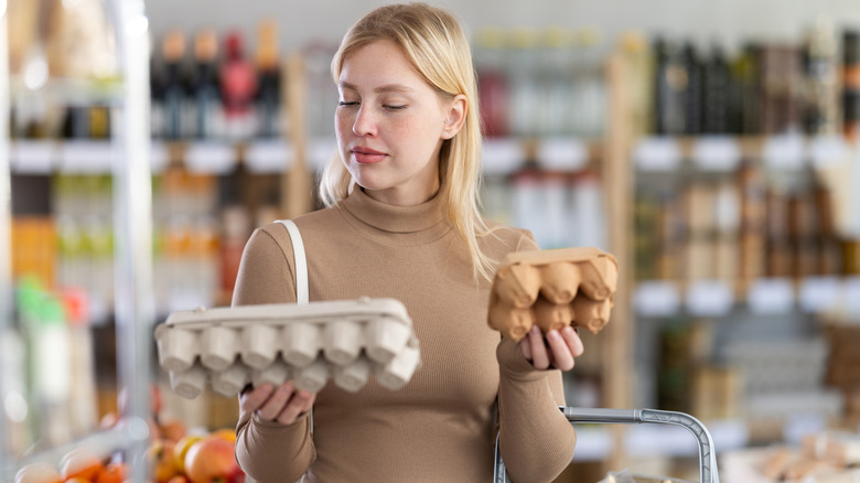 Woman comparing two cartons of eggs