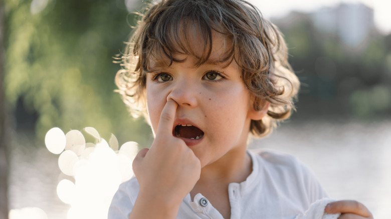 Young boy picking his nose outdoors