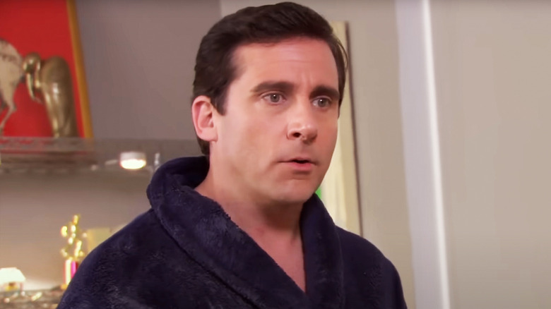 MIchael Scott wears a rob as he stands in his house in The Office