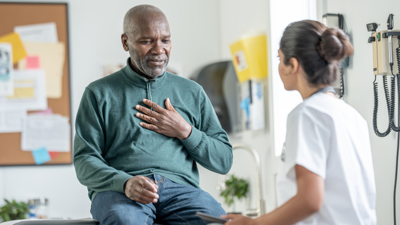 Man with hand on chest talking with a healthcare professional
