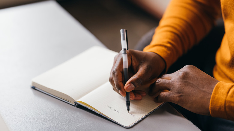 Person writing words in notebook