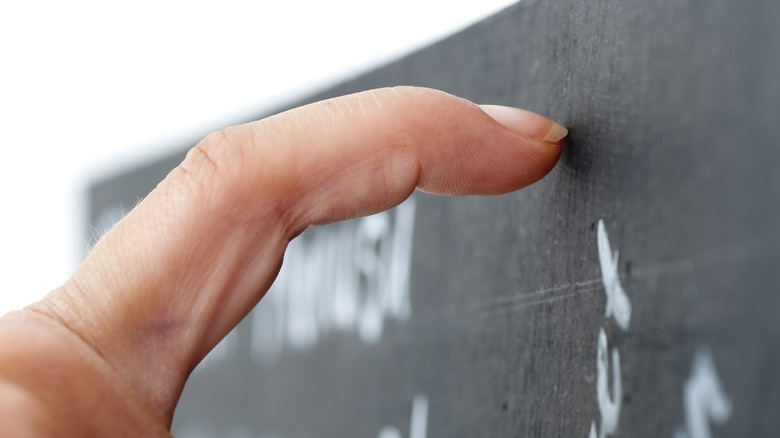 A pointer finger extended so that the fingernail is scratching a chalkboard