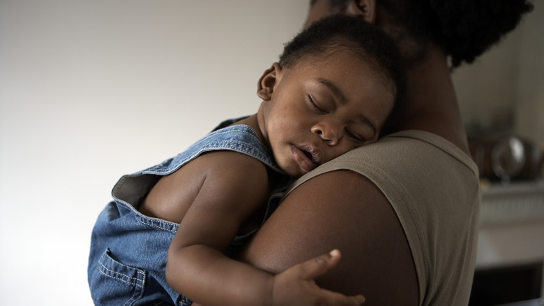 Mother holding her baby as he sleeps on her shoulder