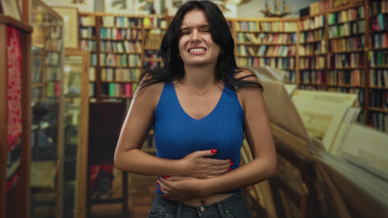 A woman clutching her stomach in a bookstore