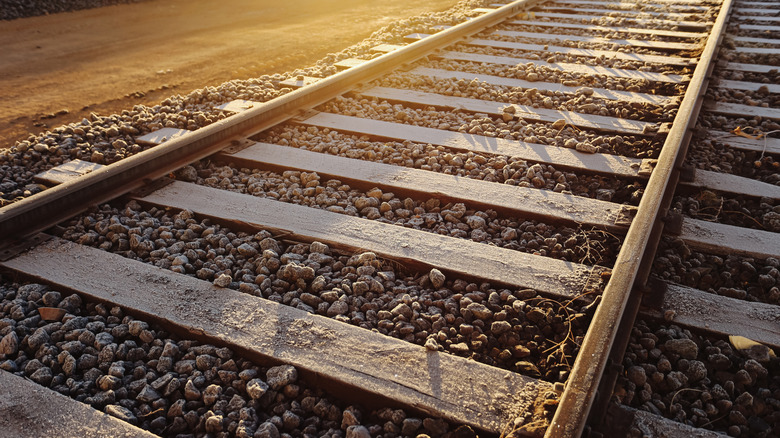 Railroad tracks made of two steel rails supported on wooden ties embedded in ballast stones
