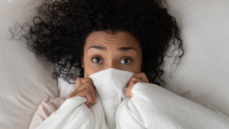 Woman hiding under blanket