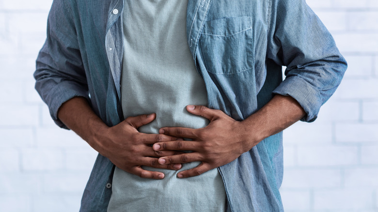 Person clutching abdomen, feeling digestive discomfort