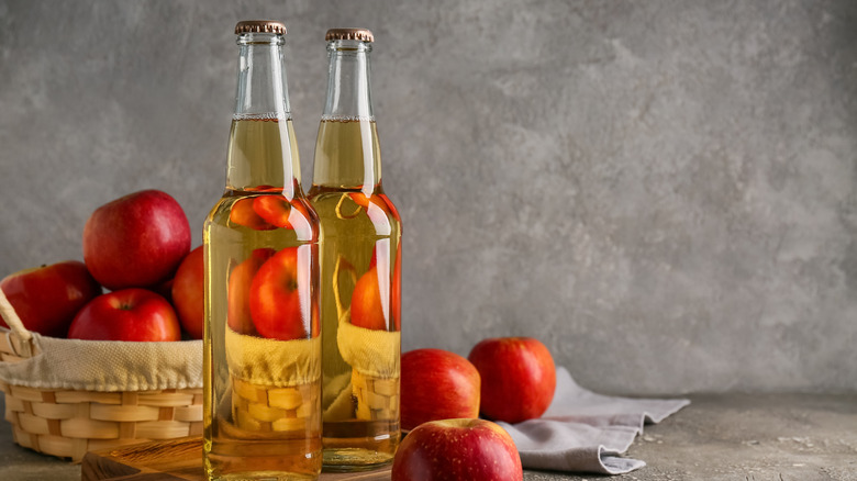 Fresh bottles of apple cider and apples in a wicker basket