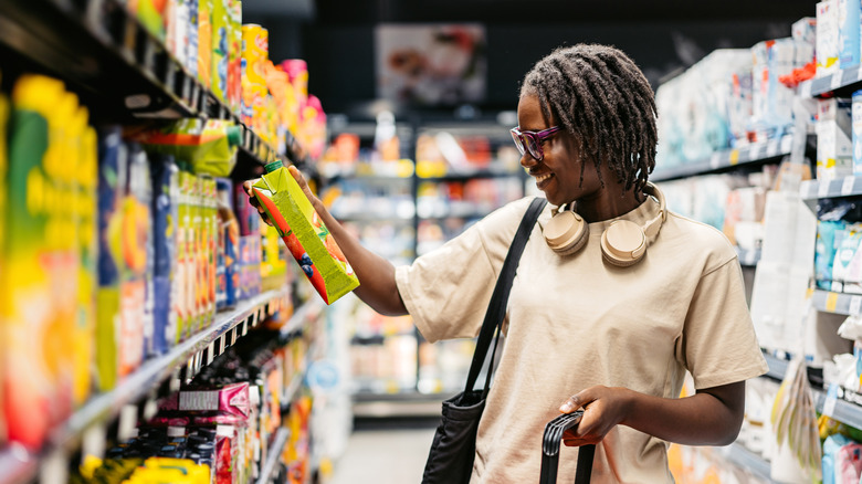 Woman looking at a container of juice in a supermarket