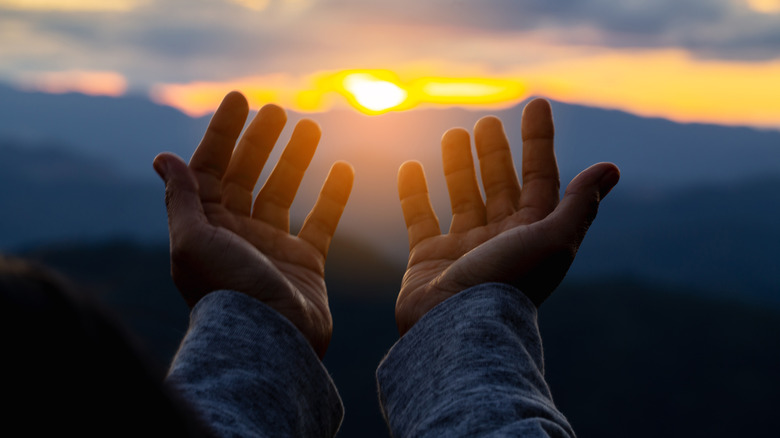 Close up of hands in front of the sun