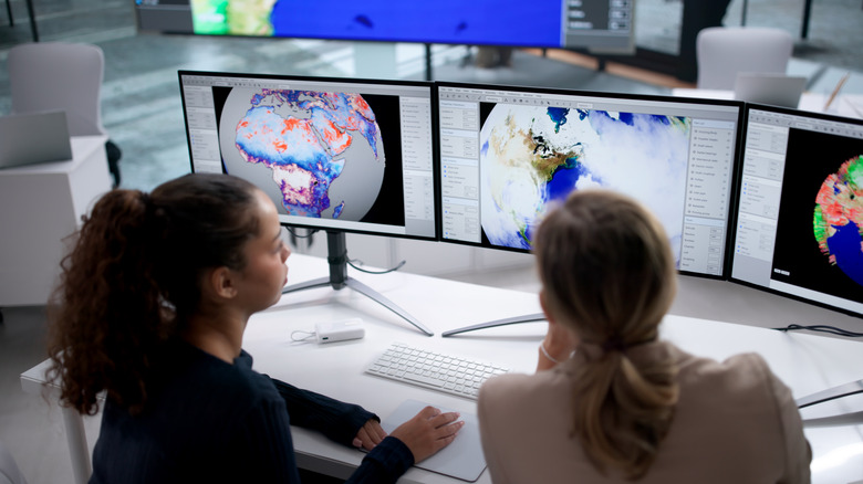 Two women analyzing weather data on computer screens