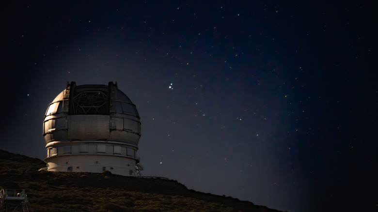 Observatory on the top of a hill in front of a starry sky