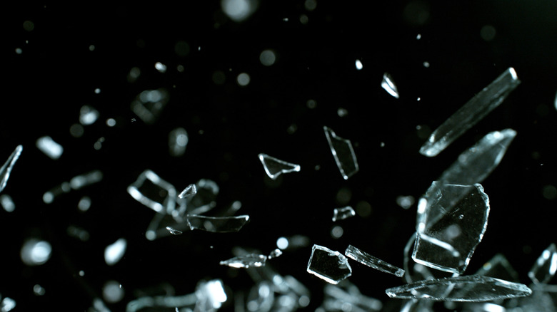 clear shattered glass falling in front of a black background