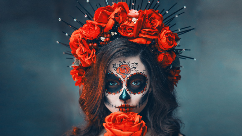 Day of the dead makeup on young woman, roses in hair, face painted like a skull