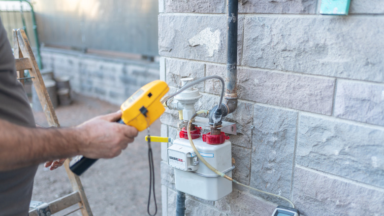 Gas technician visiting exterior gas monitor on house