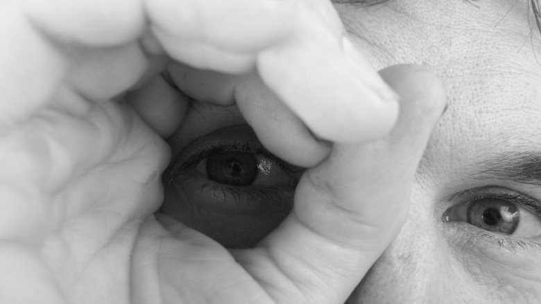 Man looking through a circle made with his hand with one eye