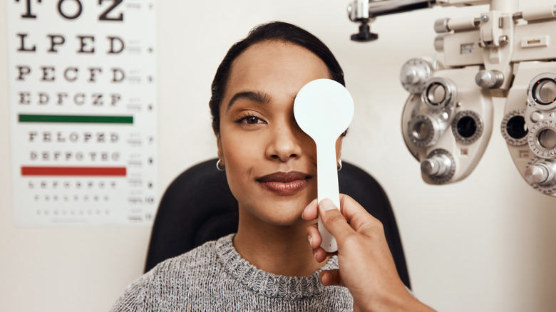 An eye doctor covers a woman's eye during an eye exam