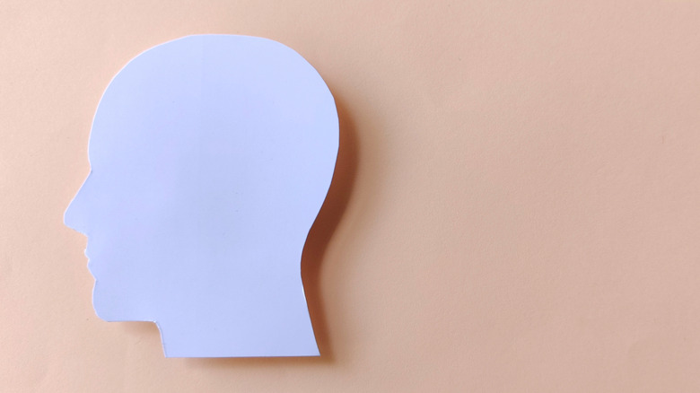 A blank white cut-out of a face on a peach background.