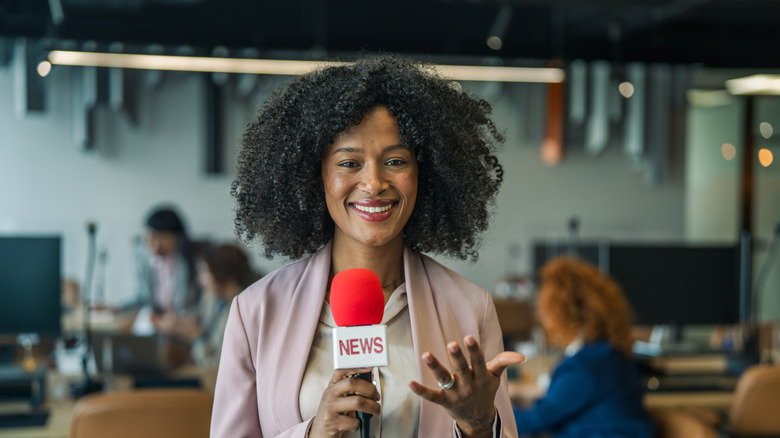 A news reporter with microphone talking into the camera