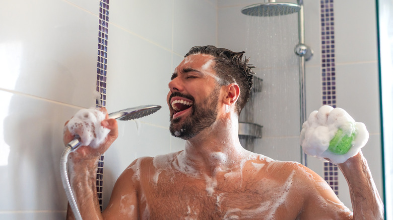 Young man singing in shower covered in soap