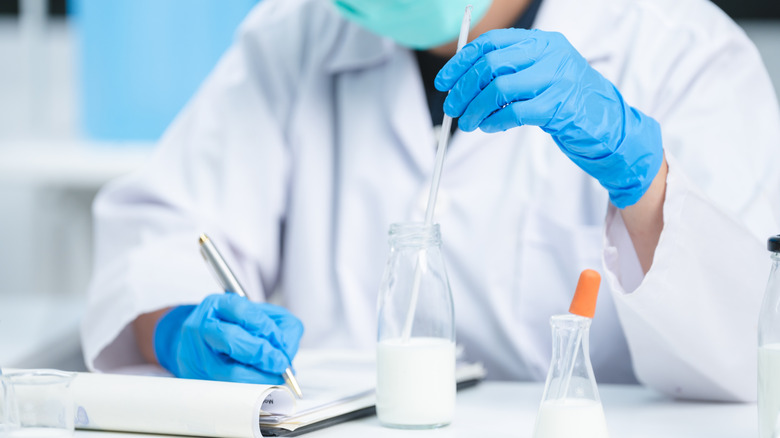 food scientist writes notes while observing a glass of milk