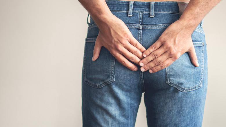 Person with both hands covering buttocks