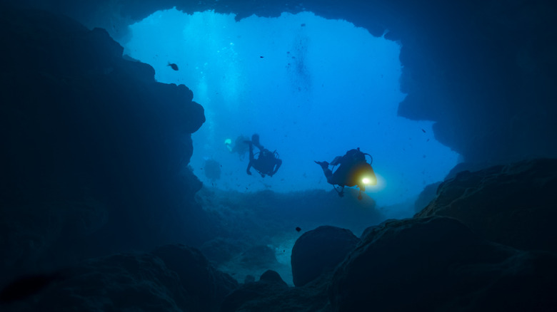 Divers exploring a dark underwater cave
