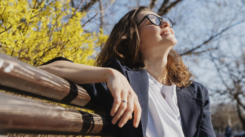 Woman sitting on a bench outdoors and smiling