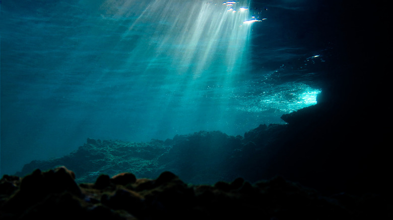 Rays of sunlight shining through ocean water onto a coral reef