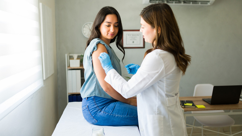 A healthcare professional is prepping a patient's arm for vaccination.