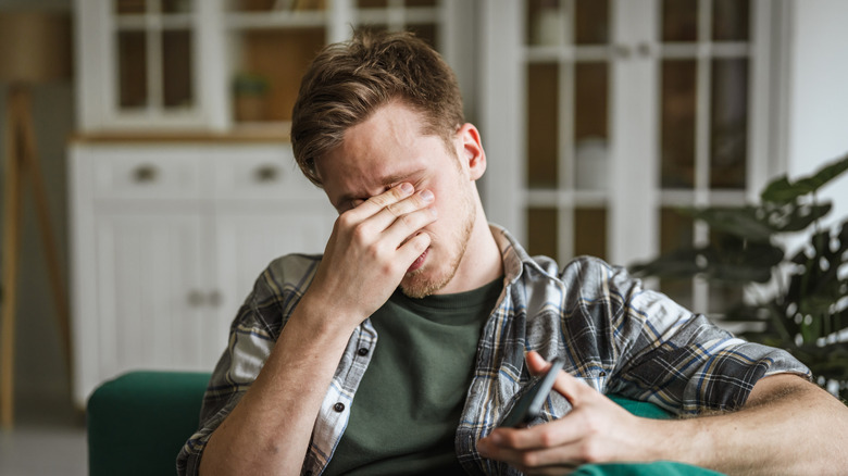 Young person with hand over face, feeling stress and exhaustion
