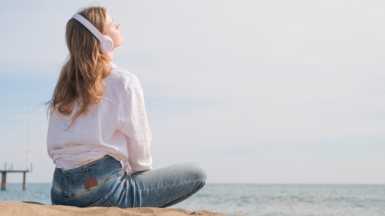 A woman listening to music on the beach.
