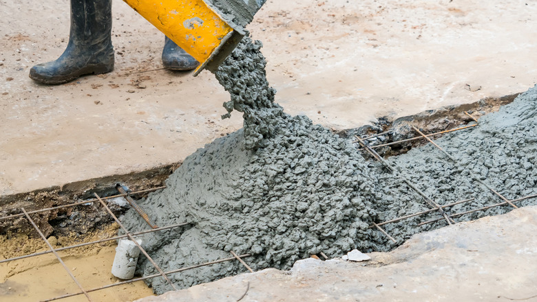 Wet concrete being poured into a gap in a sidewalk or road