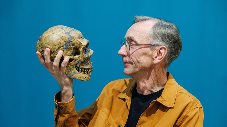 Nobel laureate Svaante Paabo holding the skull fossil of an ancient human