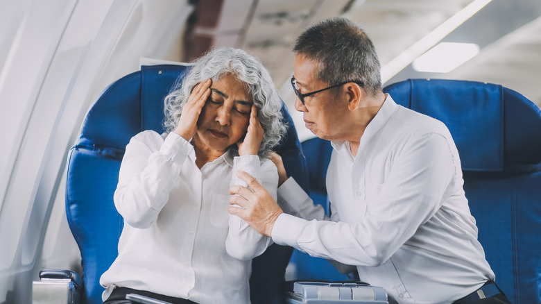 A worried-looking senior couple sitting in a plane