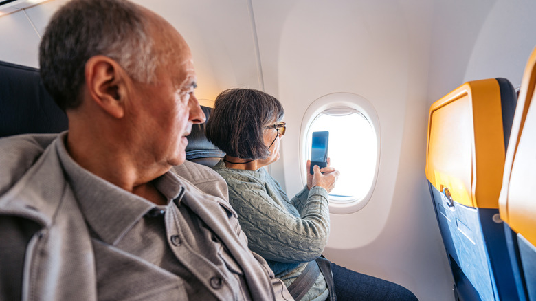 A senior couple looking out of the window in a plane