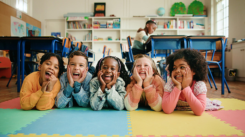 Five children laying down with smiling faces