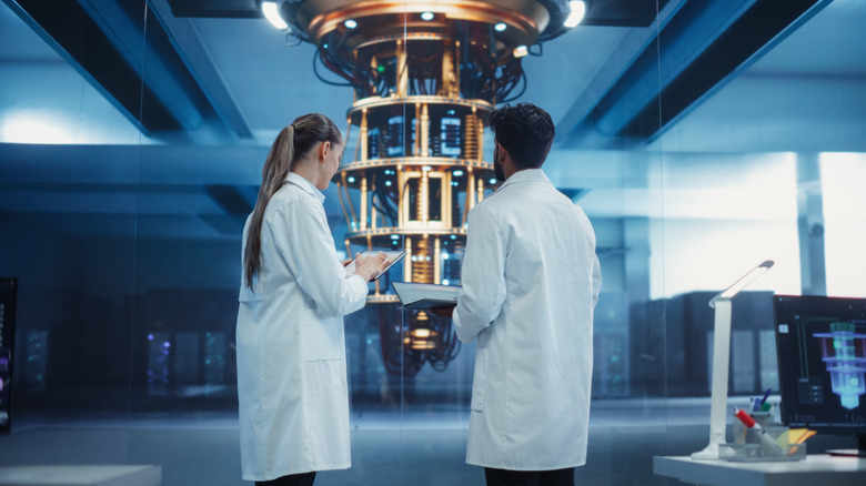 Two scientists (a man and a woman) standing in front of a quantum computer
