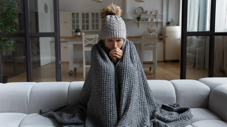 Woman wearing a hat and blanket while sitting on sofa