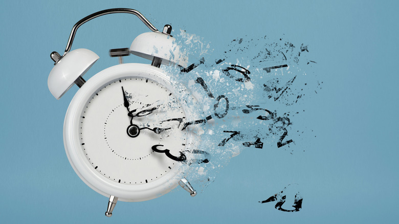 White alarm clock losing its numbers and disintegrating, demonstrating lost time