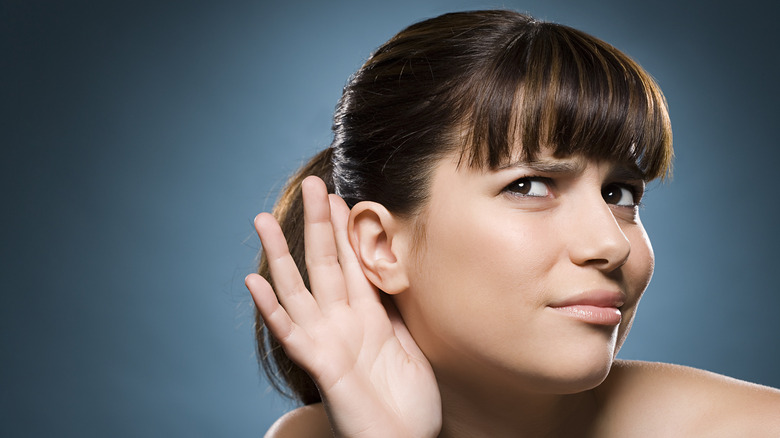 Person listening with hand behind ear