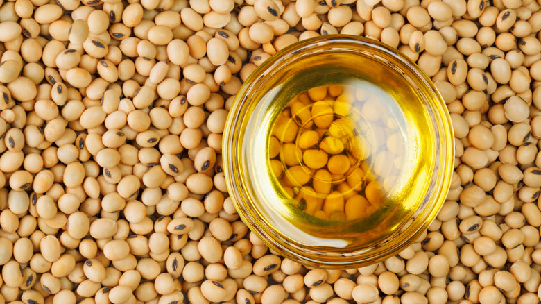 Small bowl of cooking oil on top of large pile of dried soybeans