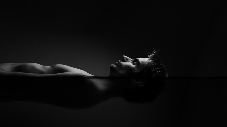 Man floating in a darkened sensory deprivation tank filled with salt water