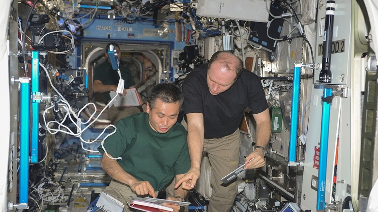 Astronauts Wakata and Kotov point to a clipboard while floating in the ISS