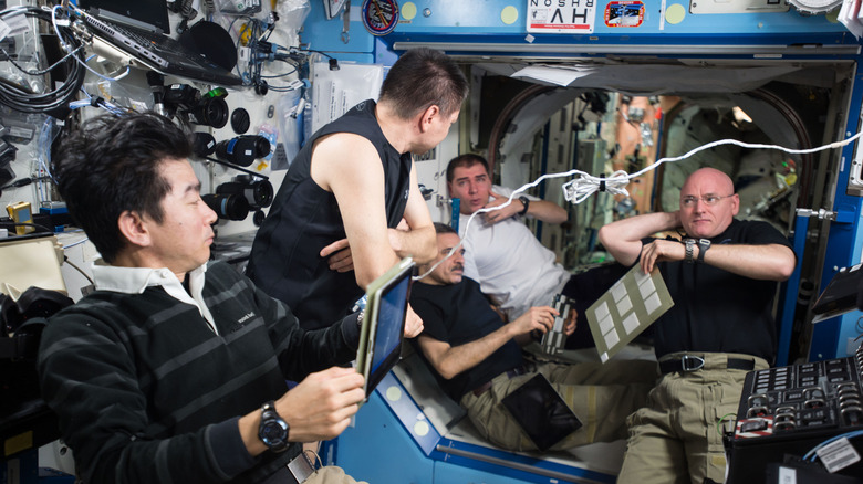 five male astronauts on the ISS in discussion surrounded by equipment