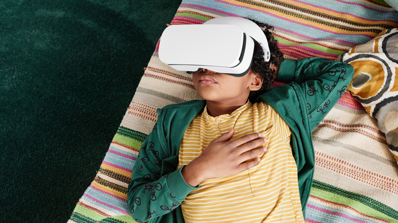 Young boy laying on patterned mattress with VR headset on