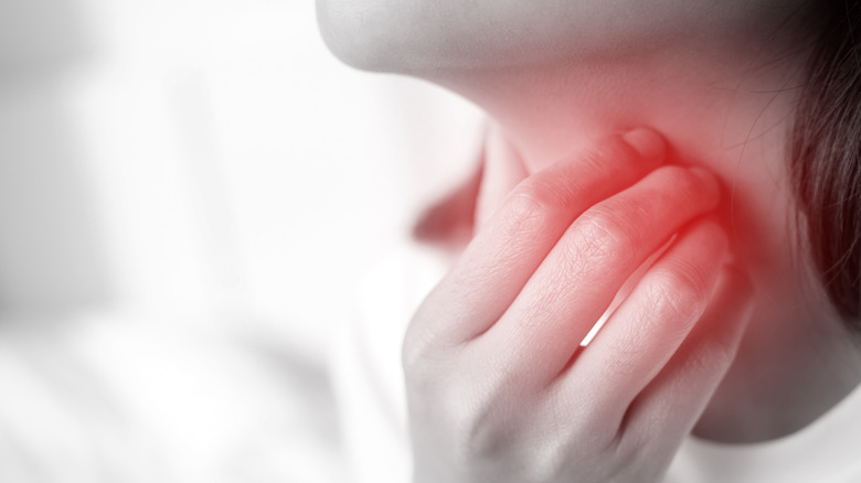 Woman holding hand up to sore throat
