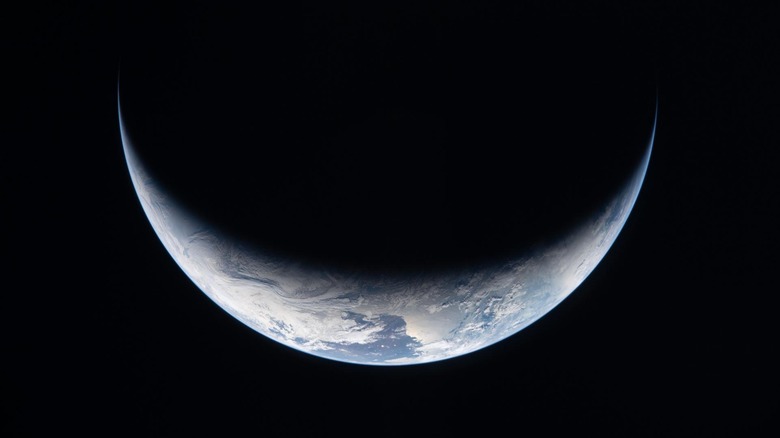 A sliver of Earth is illuminated against the blackness of space