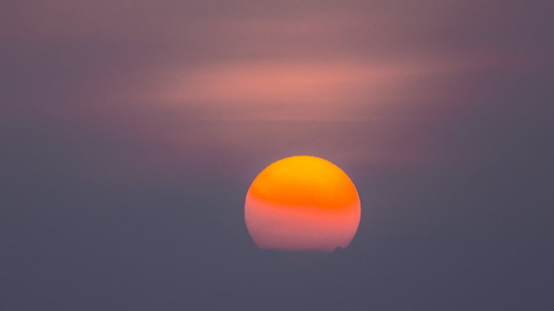 Orange sun seen through haze and clouds